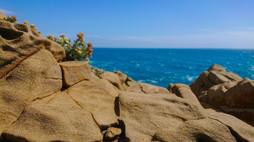 Rock formations by sea against blue sky