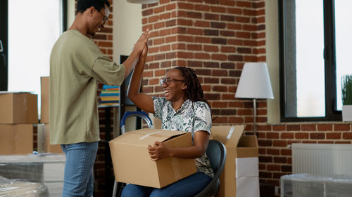 Happy man giving high five to woman holding cardboard box at home