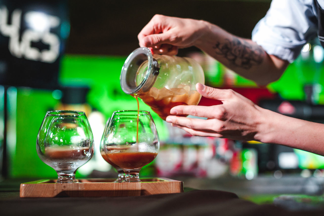 CLOSE-UP OF HAND POURING WINEGLASS IN GLASS