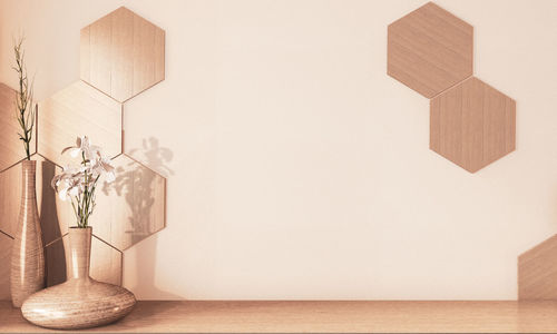 Close-up of vase on table against wall at home