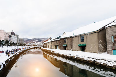 Canal amidst buildings against sky during winter