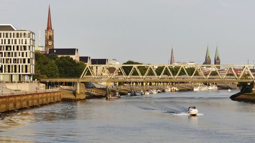 Bridge over river in city against sky