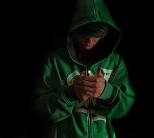 Midsection of man holding cigarette against black background