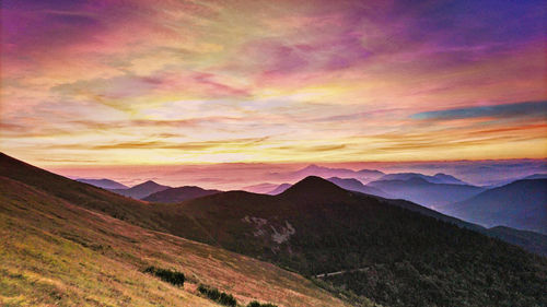 Scenic view of mountains against dramatic sky during sunset