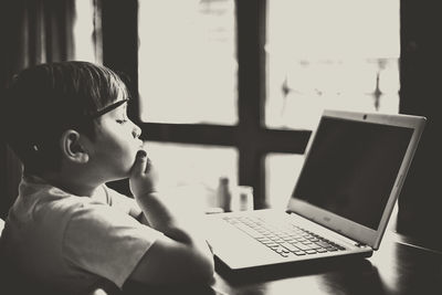 Side view of boy using laptop while sitting at table