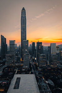 Modern buildings in city against sky during sunset