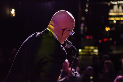 Side view of man with arms raised standing at night