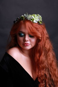 Sensuous young woman wearing wreath against black background