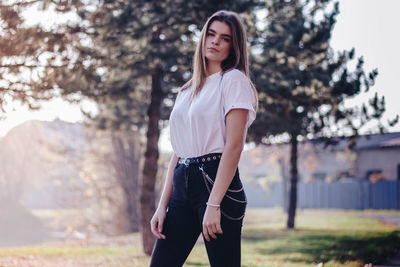 Portrait of young woman standing against trees