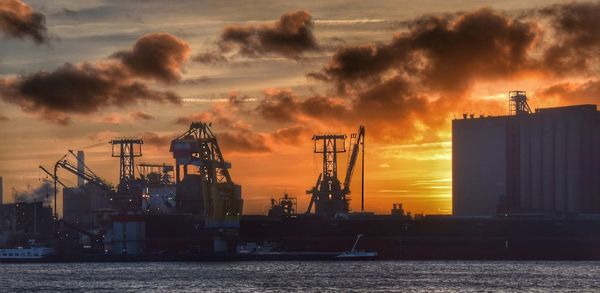 Commercial dock by sea against sky during sunset