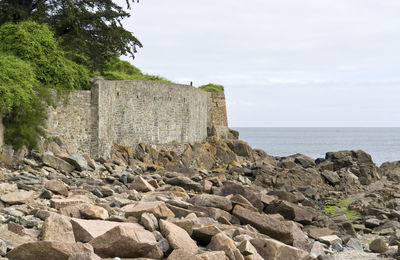 Stone wall by sea against sky