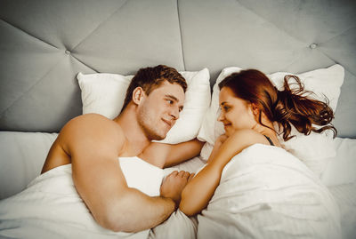 High angle view of couple romancing on bed