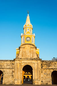 Clock tower gate against clear blue sky in city