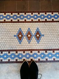 Low section of person standing on tiled floor