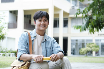 Portrait of smiling young man sitting against building