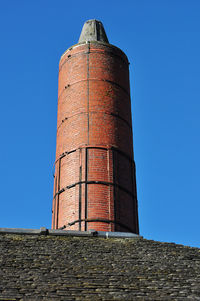 Low angle view of factory against clear blue sky