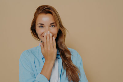 Portrait of young woman standing against pink background
