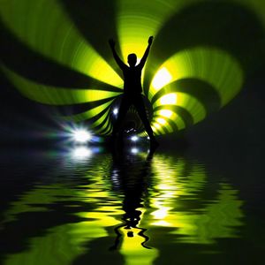 Silhouette person standing in illuminated water at night