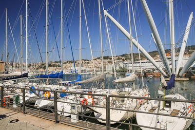 Sailboats moored at harbor against blue sky