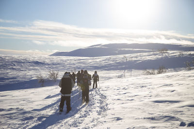 People splitboarding on snow covered landscape