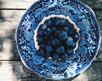 Directly above view of fresh blueberries in blue porcelain plate on table