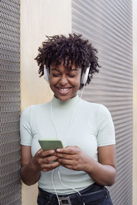 Beautiful young woman with afro hair and headphones listening to music smiling and happy 