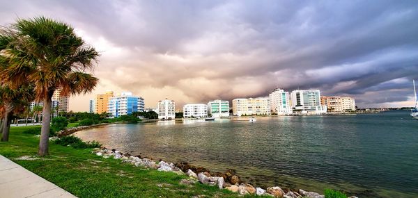 City buildings by sea against sky