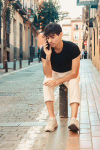 Side view of young man using mobile phone while standing in city