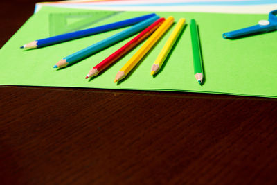 Colorful pencils with paper on table