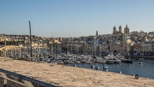 Sailboats moored at harbor against clear sky