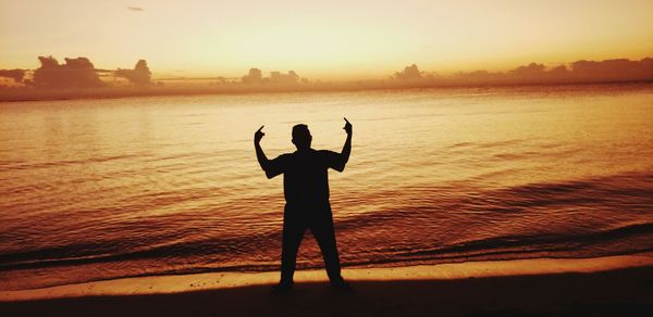 Silhouette man standing at beach during sunset