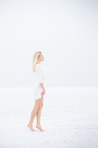 Side view of woman standing in sea against clear sky