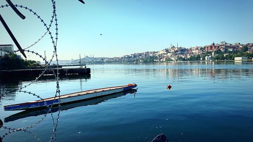 Sailboats moored on river against clear blue sky