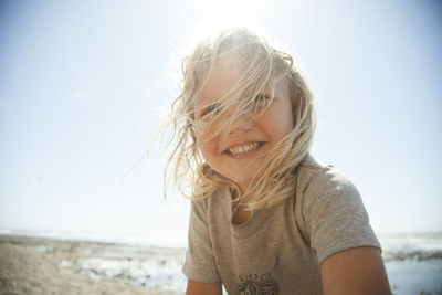 Happy girl at beach against clear sky