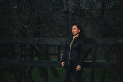 Woman standing by railing in forest