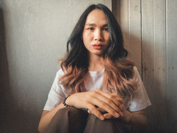 Portrait of young woman against wall