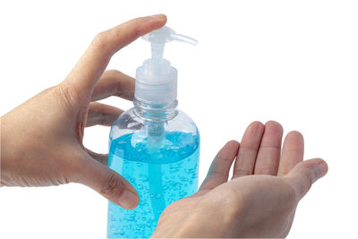 Close-up of hand holding glass bottle against white background