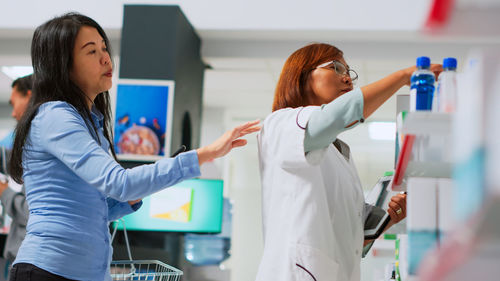 Side view of young woman with arms raised in laboratory