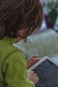 Boy using digital tablet while sitting on bed at home