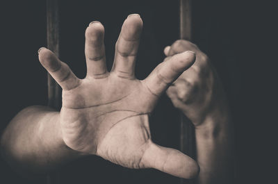 Cropped hands of woman reaching in prison