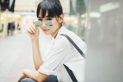 Portrait of beautiful young woman wearing sunglasses at sidewalk