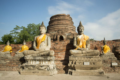 Buddha statues outside temple against blue sky