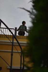 Low angle view of child on staircase against clear sky