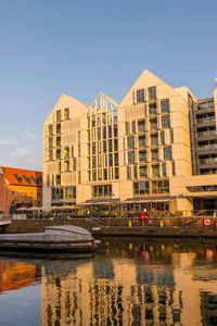 Buildings by river against sky in city