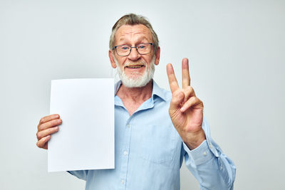 Portrait of smiling senior man gesturing against white background