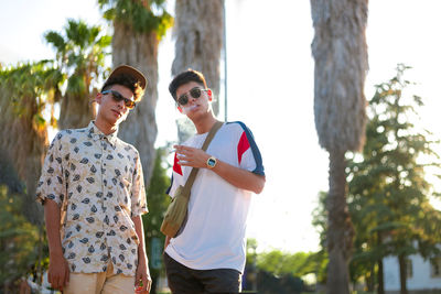 Portrait of smiling friends standing against trees