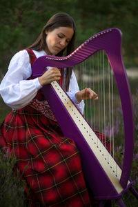 Young woman playing harp at forest