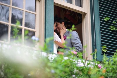 Low angle view of bride and groom standing by window