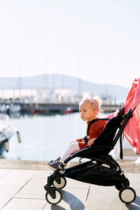 Side view of boy sitting on boat against sky