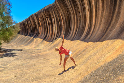 Portrait of woman standing with arms outstretched by cliff